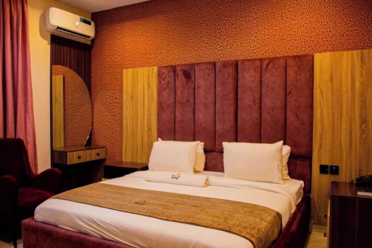 Habitación de hotel con una cama grande, un escritorio, una silla y un equipo de aire acondicionado.