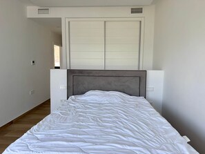 Ein Schlafzimmer mit einem Bett, einer geschlossenen Schiebetür und einem Wandlüfter.