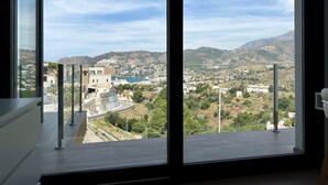 Ett stort fönster med utsikt över en stad och kullar.