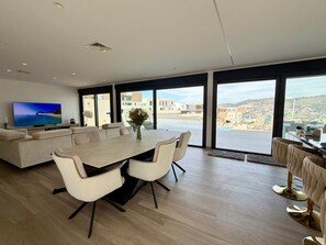A modern living room with a large TV, a dining table, and a sofa. - Casa Montemar (Almuñécar)