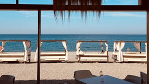 En avslappnad lounge vid stranden med träbänkar och ett bord, med utsikt över havet.