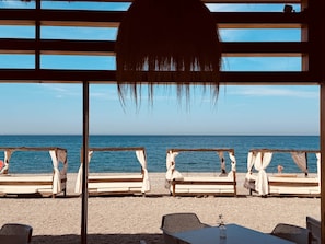 A beachside lounge with wooden benches and a table, overlooking the sea. - Casa Montemar (Almuñécar)