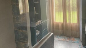 A room with a stone wall, a built-in shelf, a door with a curtain, and a tiled floor. - L' ARC EN CIEL (Pujaut)