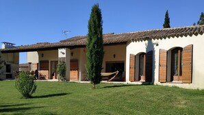 A building with a tiled roof, a grassy lawn, and a hammock. - L' ARC EN CIEL (Pujaut)