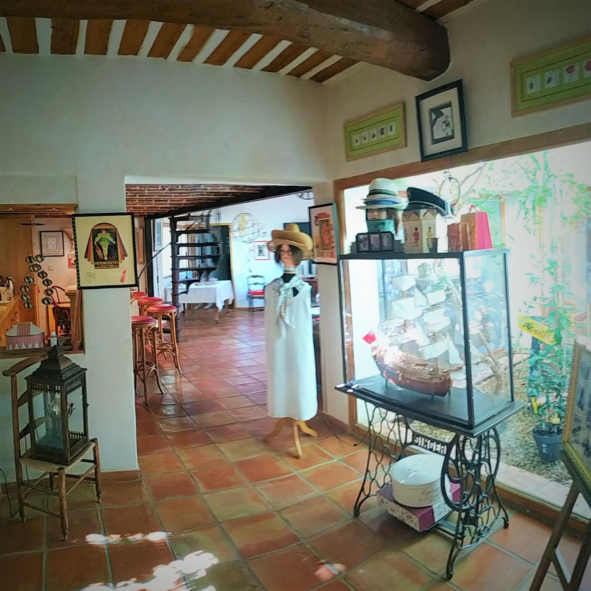 A room with a tiled floor, a sewing machine, a mannequin, and a bookshelf.