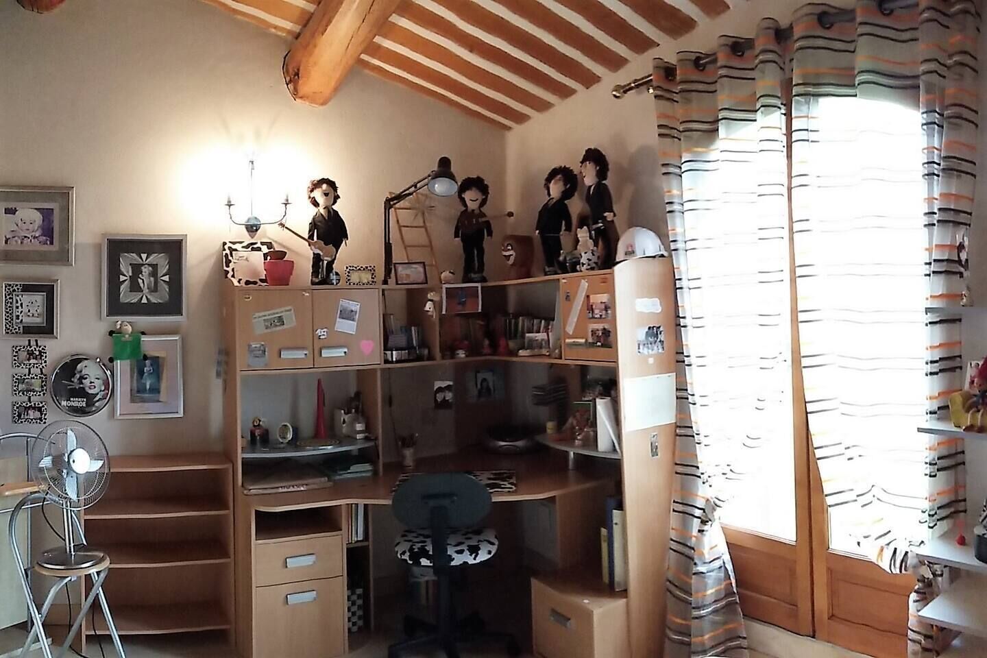 Quarto com beliche, escrivaninha, cadeira e ventoinha.