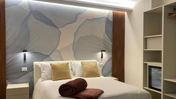 A bedroom with a bed, nightstands, a wardrobe, and a wall with a unique design.