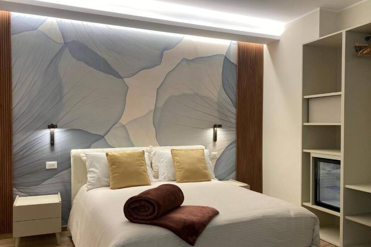 A bedroom with a bed, nightstands, a wardrobe, and a wall with a unique design.