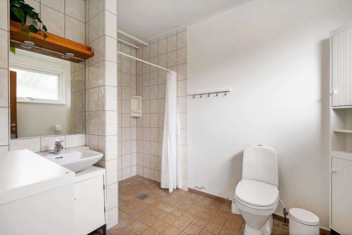 A bathroom with a sink, toilet, shower, and a mirror.