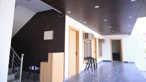 Un intérieur moderne avec un comptoir d’accueil en bois, un escalier et un couloir menant à une porte.