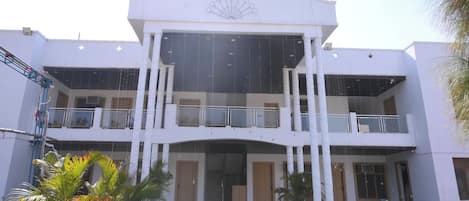 Un edifici de diversos pisos amb un atrium central, balcons i una escala que condueix a l'entrada.