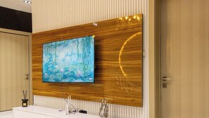 Un baño moderno con un espejo grande, un tocador de madera y un televisor de pared grande.