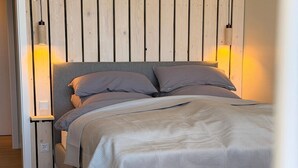 A bedroom with a bed, bedside tables, a wooden wall, and a nightstand. - Exclusive apartment with sea view in Haus Seeblick! - Lake view (Borkum)