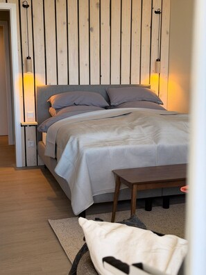 Ein Schlafzimmer mit einem Bett, Nachttischen, einer Holzwand und einem Beistelltisch.
