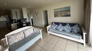 A living room with a sofa, a dining area, and a kitchen. - Mangrove Beach Estate Boboyi (Port Shepstone)