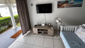 A room with a TV, a fan, a wooden cabinet, a sofa, and a painting on the wall. - Mangrove Beach Estate Boboyi (Port Shepstone)