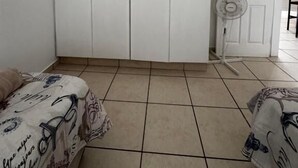 A bedroom with a large white wardrobe, a bed with patterned bedding, a standing fan, and a door with nautical-themed stickers. - Mangrove Beach Estate Boboyi (Port Shepstone)