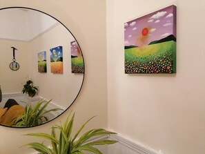 Ein Flur mit einem großen Spiegel, einem Wandbild eines Sonnenuntergangs und mehreren gerahmten Kunstwerken.