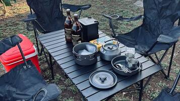 Un espacio para comer al aire libre con sillas, una mesa y equipo de camping.