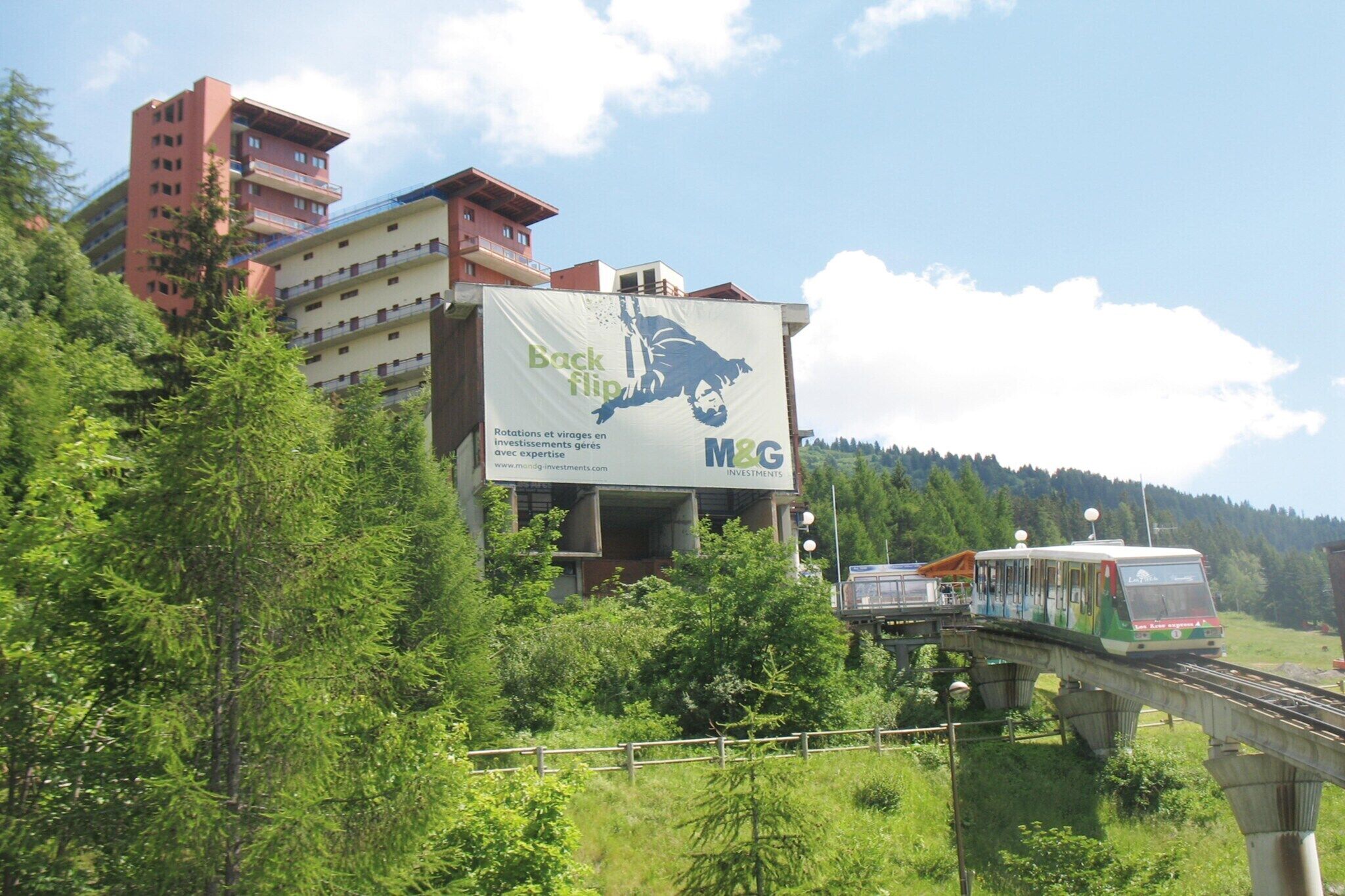 A train station with a billboard advertising 'Back flip' and 'M&G Investments.'