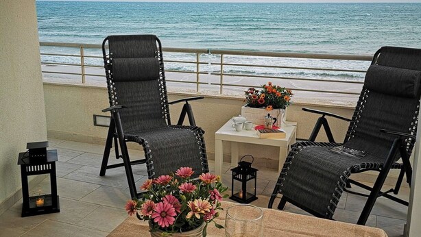 A dining area with a table set for two, overlooking the ocean. - Appartamento Tramonto sul Mare (Caucana)