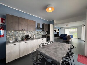 A modern kitchen with a dining area, a fire extinguisher, and a view of the outdoors. - A Casa di Chica by Geco Vacation Rentals (Marina Di Ragusa)
