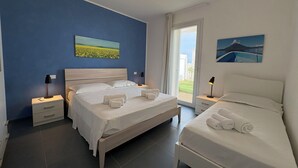 Ett hotellrum med en stor säng, en mindre säng, ett nattduksbord och ett litet bord vid sängen samt ett fönster med utsikt.