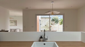 A modern kitchen with a white sink, wooden countertop, and a view of the outside. - New wooden house less than 5 minutes from the beach (Gouville-sur-Mer)