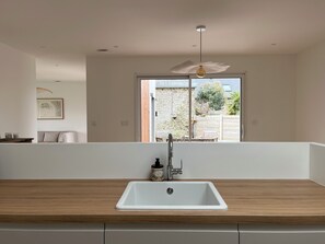 Eine moderne Küche mit einem weißen Spülbecken, einer Holz Arbeitsplatte und Blick ins Freie.