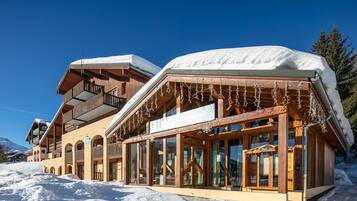 Un bâtiment en bois doté de balcons et de grandes fenêtres, entouré de neige.