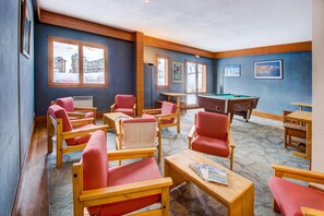 Une pièce meublée de meubles en bois, avec une table de billard et des tableaux encadrés accrochés aux murs.