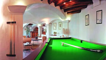 Una mesa de billar en una sala con techos abovedados y una chimenea.