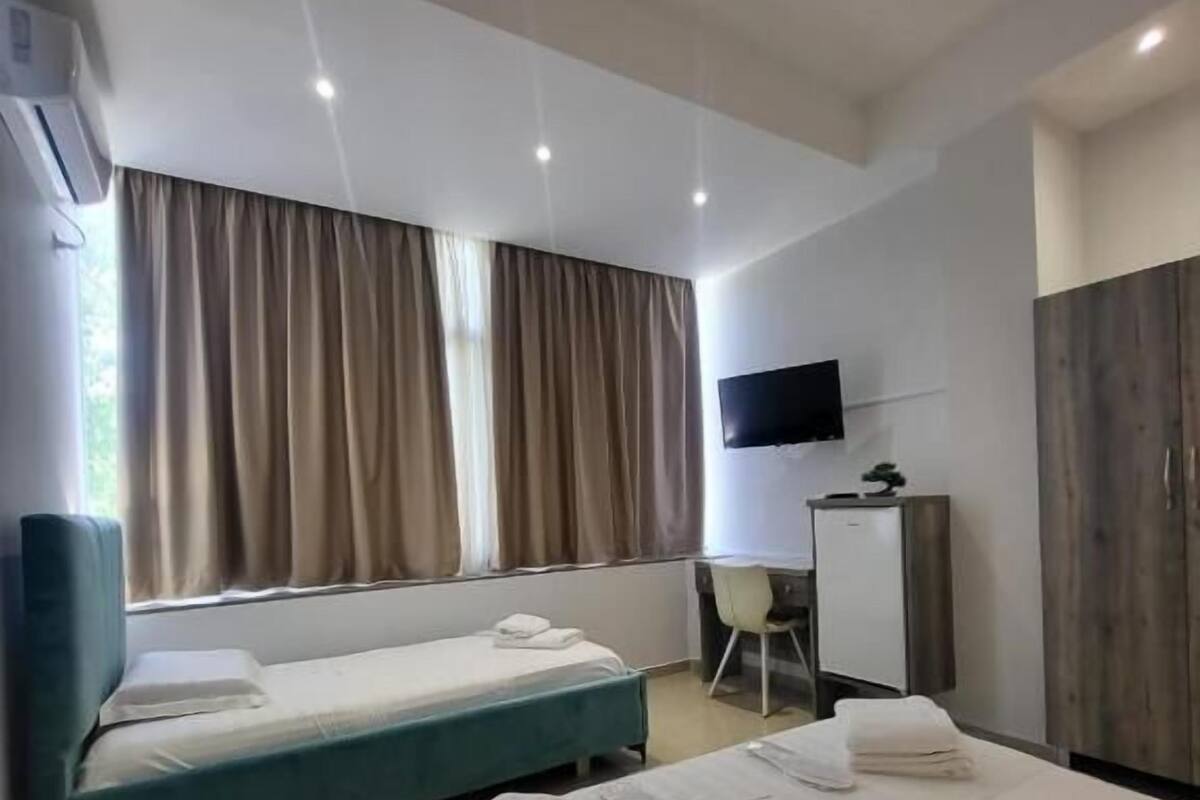 A hotel room with two beds, a desk, a chair, a TV, and a wardrobe.