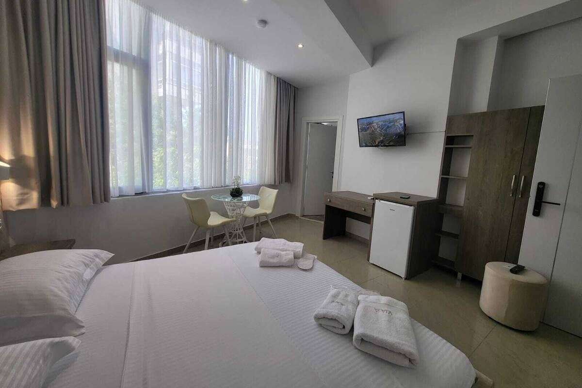 A hotel room with a bed, a desk, a chair, a television, and a wardrobe.