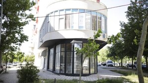 A modern building with a curved facade, large windows, and a paved area with trees. - Alv Rent Room (Vlorë)
