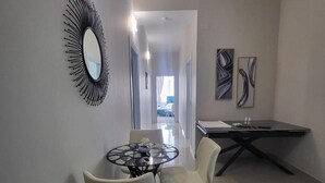 A modern dining area with a round table, two chairs, a black and white abstract painting, and a black wall-mounted mirror. - Alv Rent Room (Vlorë)