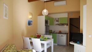 A compact kitchen with a dining area, including a white table, chairs, and a hanging light fixture. - Family duplex with patio (Saint-Cyprien)