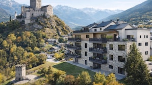 Un castillo en una colina, con un edificio moderno al frente.