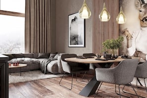 Ein modernes Wohnzimmer mit einer Couch, Esstisch, Stühlen, Pendelleuchten, einem gerahmten Kunstwerk und einer Topfpflanze.