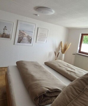 Ein Zimmer mit zwei Betten, einem Heizkörper und gerahmten Bildern an der Wand.
