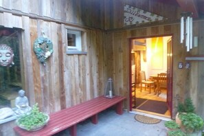 A wooden building with a bench, a small table, and a statue. - Holiday home in the meadows (Kall)