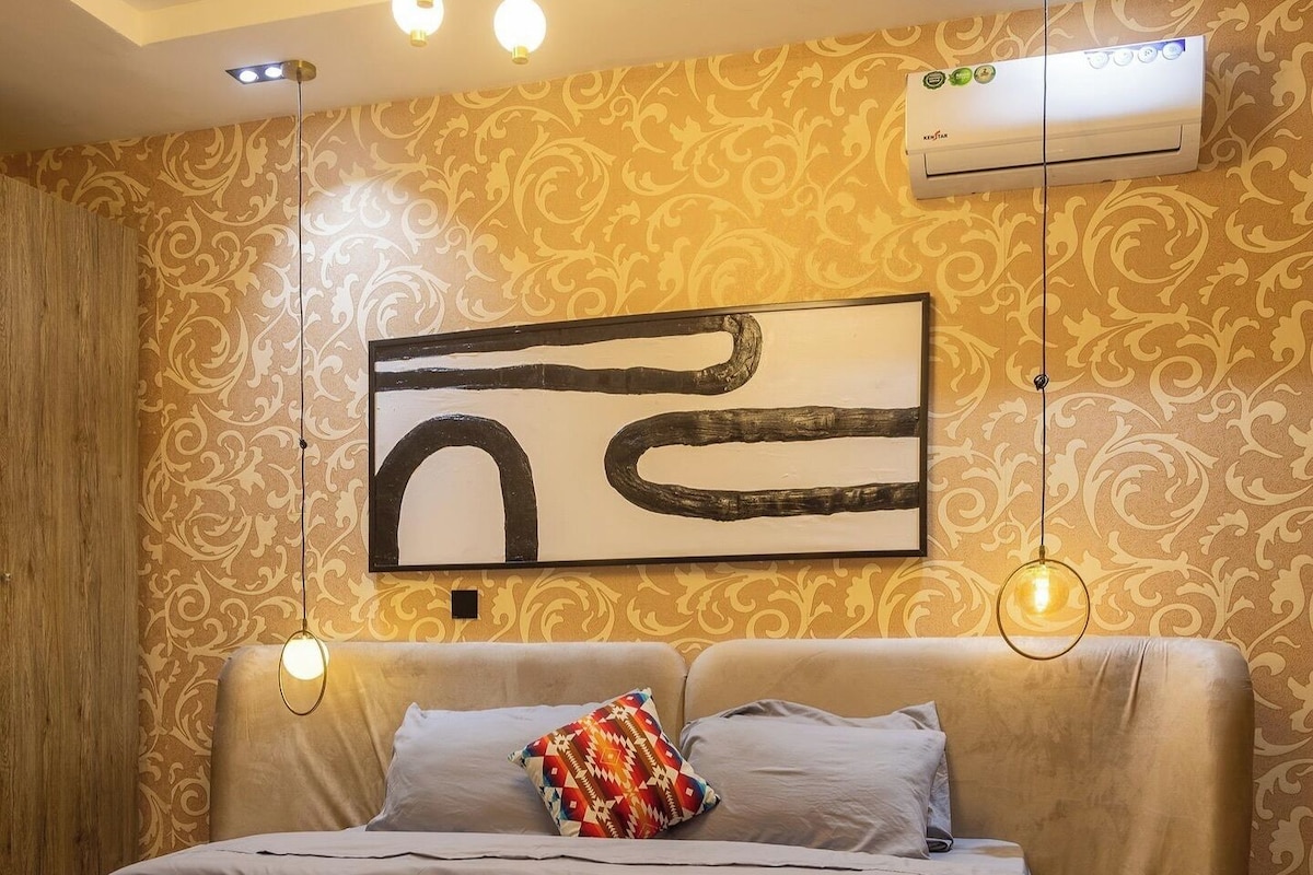 Un dormitorio moderno con una cama grande, una lámpara en el techo y un equipo de aire acondicionado.