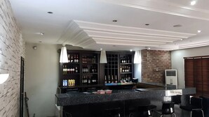 Eine Bar mit Theke, Flaschenregalen und Barhocker.