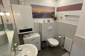 Een kleine badkamer met toilet, wastafel en een kastje.