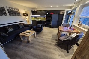 A modern living room with a sofa, armchair, coffee table, and dining table. - Holiday apartment with 1 bedroom (Oberstdorf)