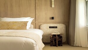 Una habitación de hotel con cama, una mesita, una lámpara de pared y una cortina.