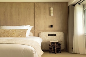 Ein Hotelzimmer mit Bett, einem kleinen Tisch, einer Wandleuchte und einem Vorhang.