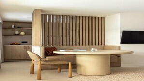 Una sala de estar moderna con una mesa redonda, un sofá, una zona de comedor y un televisor montado en la pared.