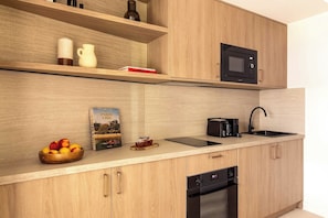 Eine moderne Küche mit Holzausstattung, einer Mikrowelle, einem Spülbecken und einem Geschirrspüler.