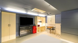 A compact room with a flat-screen TV, a red refrigerator, a dining table with chairs, and built-in cabinets. - 747 Motel (Gimcheon)